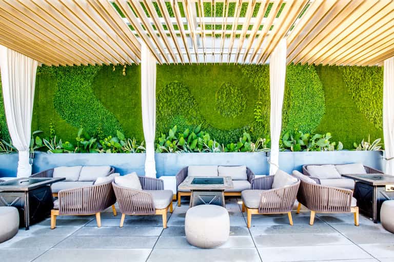 Outdoor lounge area with living walls, wooden pergola, contemporary seating, and planters