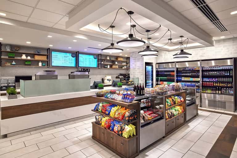 Modern convenience store interior with checkout counter, snack displays, and refrigerated beverage cases