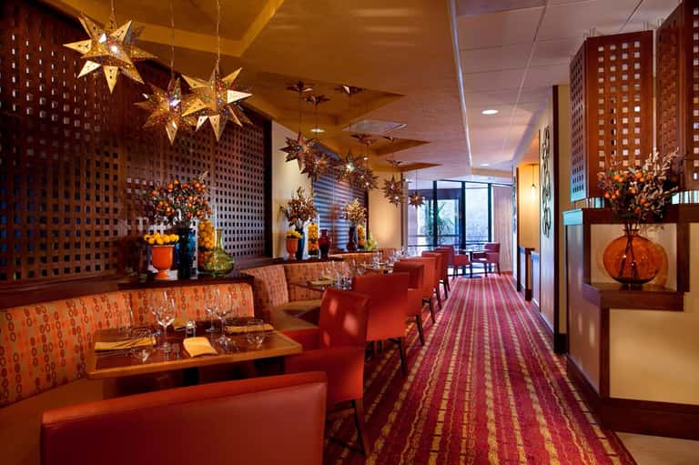 Elegant restaurant dining area with red and orange seating, decorative golden stars, and latticed wooden walls