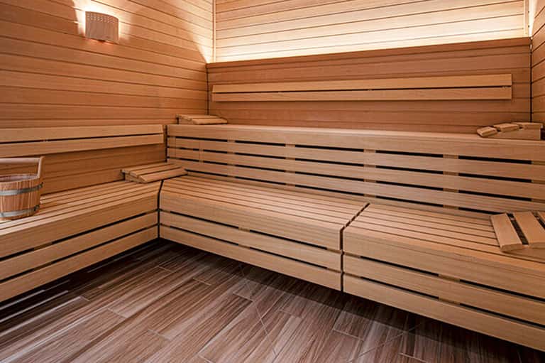 Modern sauna interior with wooden benches, horizontal slats, and soft lighting throughout