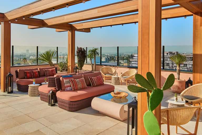 Rooftop terrace with wooden pergola, burgundy seating, and panoramic city skyline views