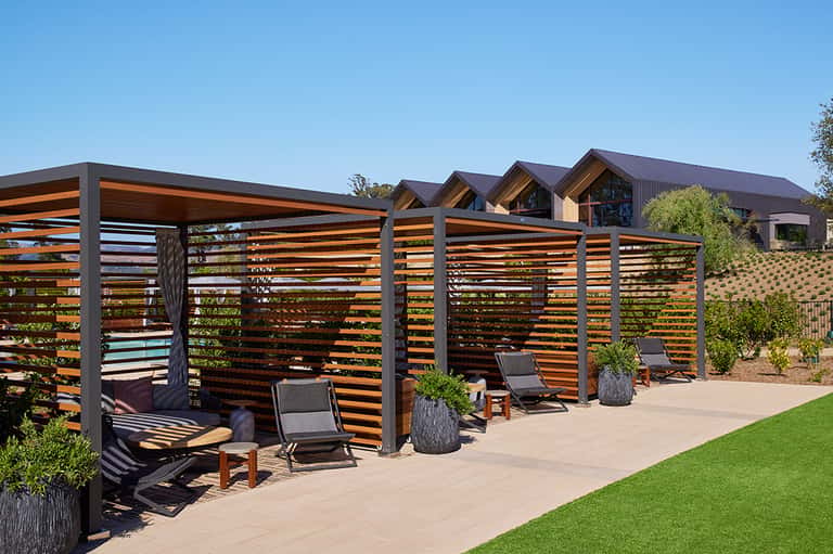 Outdoor wooden lounge pavilions with horizontal slat screening, modern seating, and manicured lawn