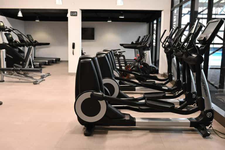 Modern fitness center with rows of black and white elliptical machines and cardio equipment