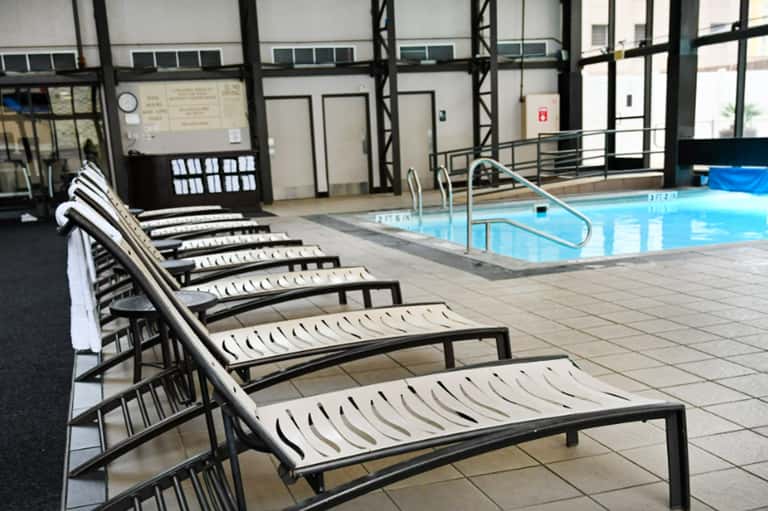 Indoor pool area with lounge chairs and large windows in a hotel facility
