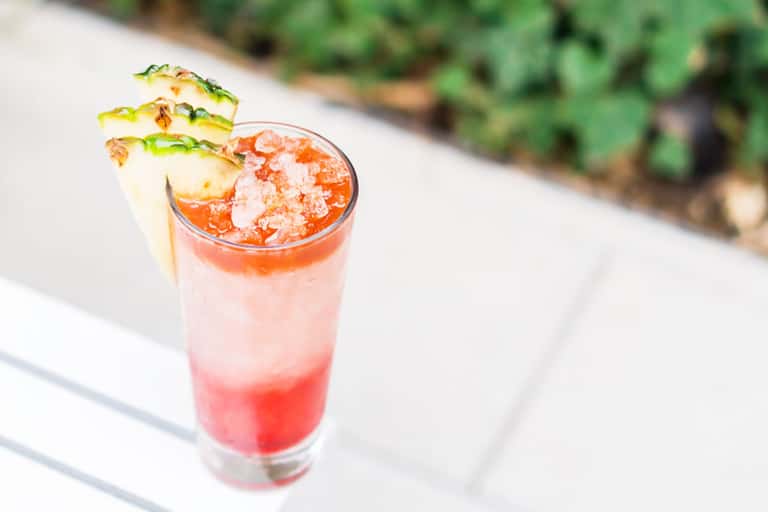 Tropical cocktail with pineapple garnish and crushed ice on outdoor patio
