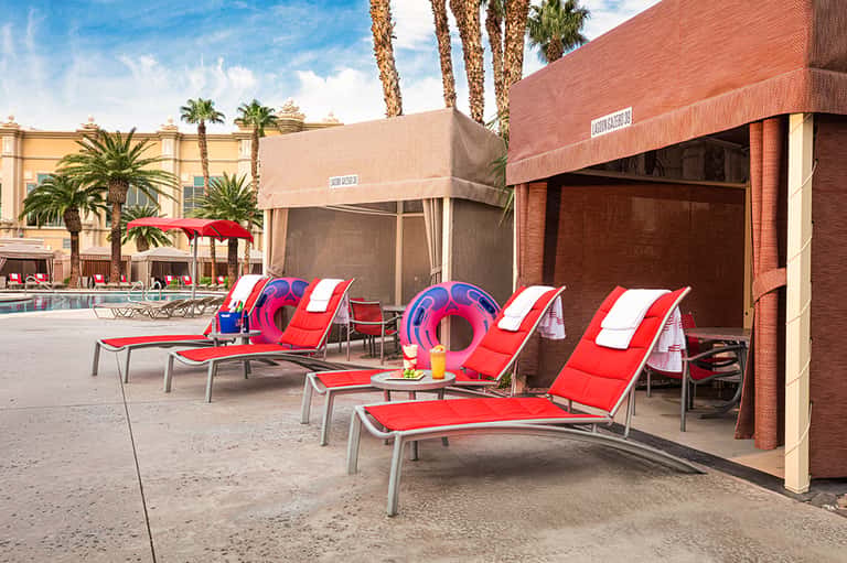 Colorful red and white lounge chairs with inflatable pool rings near brick building
