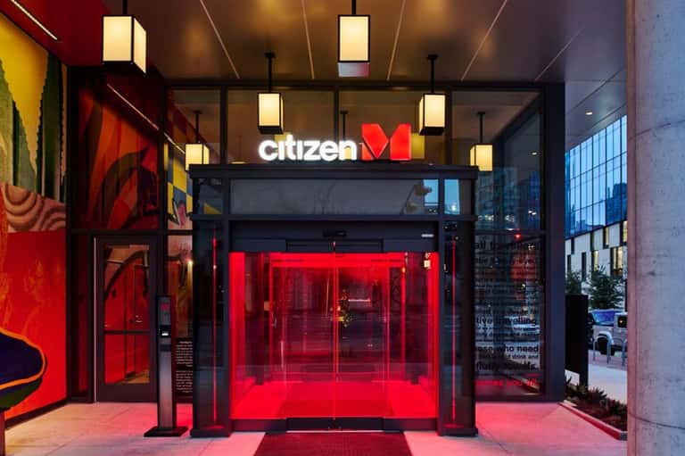 Citizen M hotel storefront entrance with illuminated red glass facade and logo signage