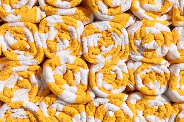 Stack of yellow and white rolled towels displayed closely together