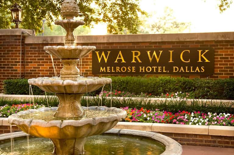 Warwick Melrose Hotel Dallas entrance with ornate fountain and colorful flower beds