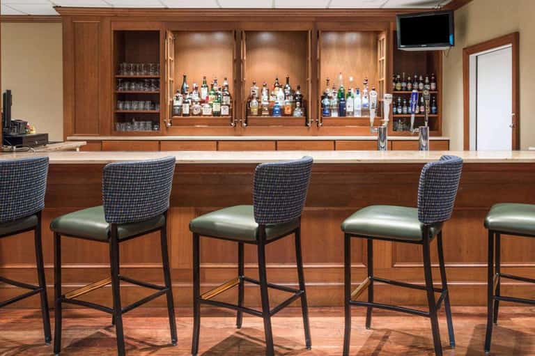 Full-service bar with wood cabinetry displaying multiple liquor bottles and bar seating