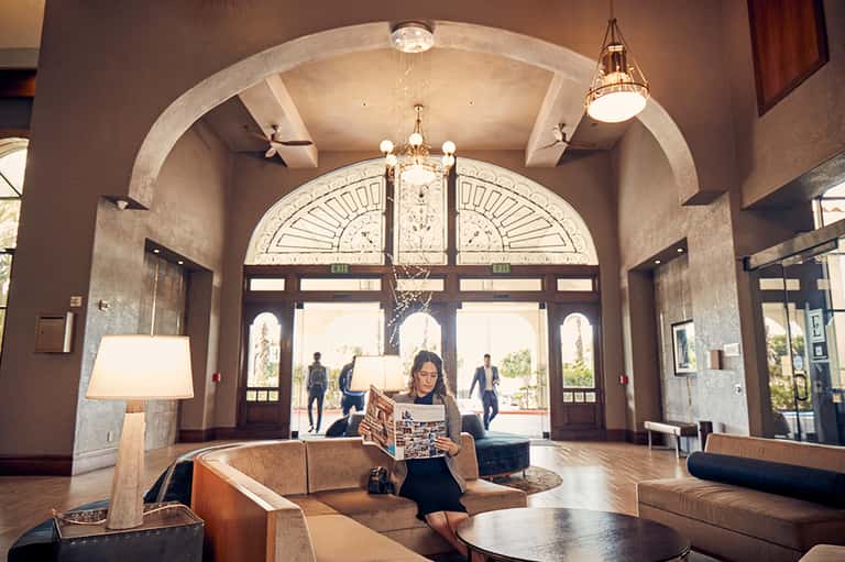 Elegant hotel lobby with arched ceiling, ornate doors, tan leather seating, and pendant lighting