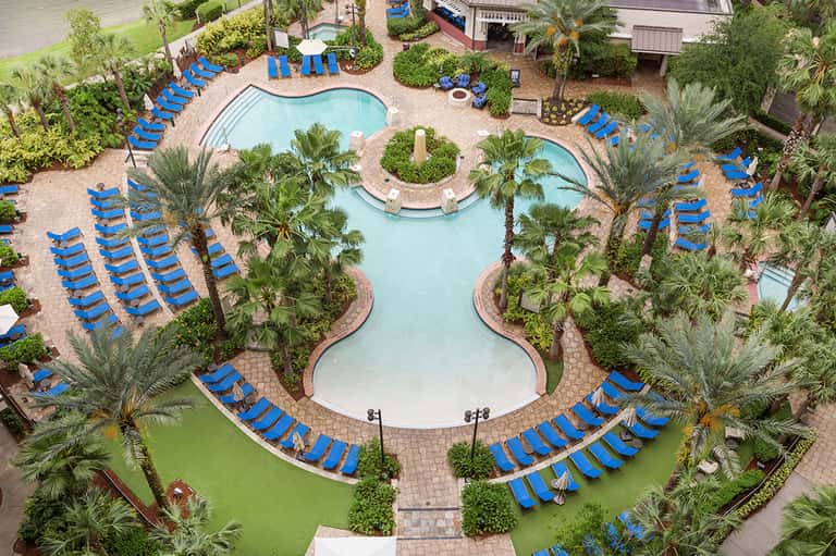 Aerial view of resort pool complex with blue loungers and palm trees