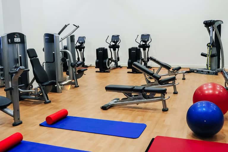 Modern fitness center with cardio equipment, exercise balls, and yoga mats on wooden flooring