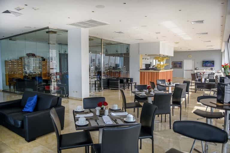 Modern hotel lounge with black furniture, glass partitions, and orange accent details