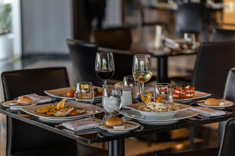 Fine dining table set with wine glasses, appetizers, and gourmet dishes