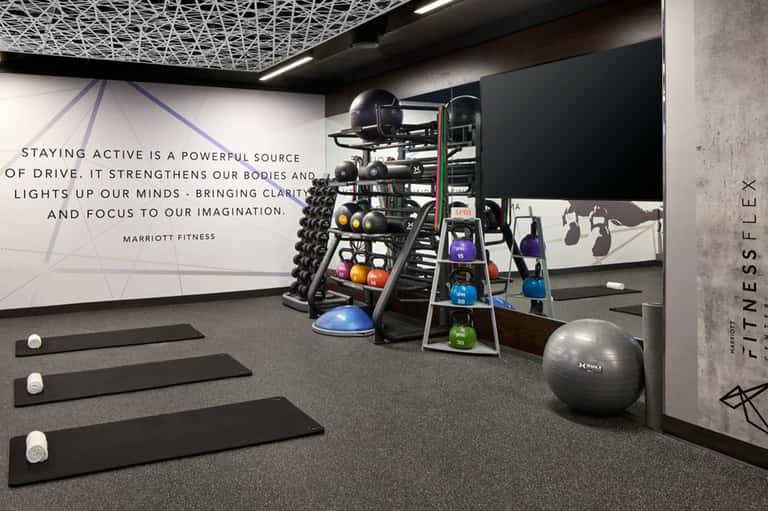 Modern fitness center with dumbbells, kettlebells, exercise mats, and motivational signage