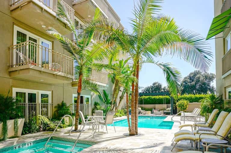 Tropical resort courtyard with palm trees, lounge chairs, and turquoise swimming pools