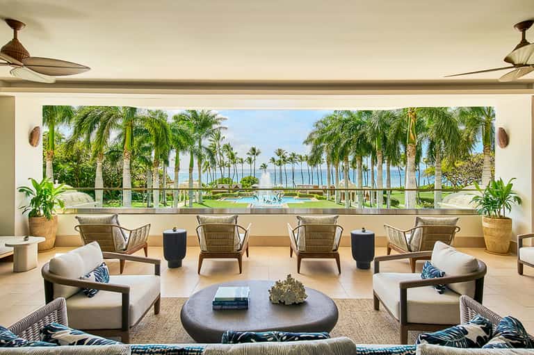 Luxury lounge with ocean view overlooking palm-lined resort grounds and pool