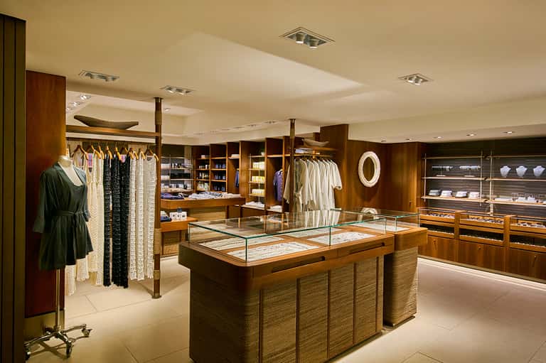 Upscale boutique retail shop with clothing racks, wooden display cases, and jewelry showcases