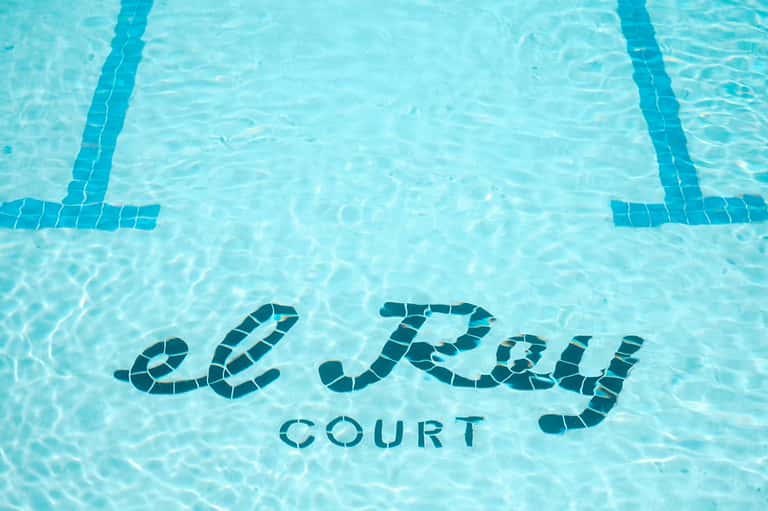 Le Parc Court pool bottom text visible in clear turquoise water with lane dividers