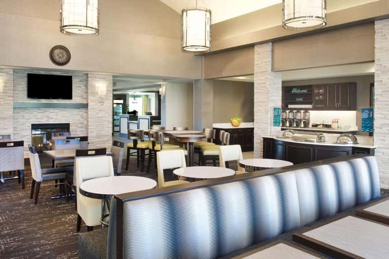 Contemporary hotel lobby with fireplace, seating areas, pendant lighting, and modern furniture in neutral tones
