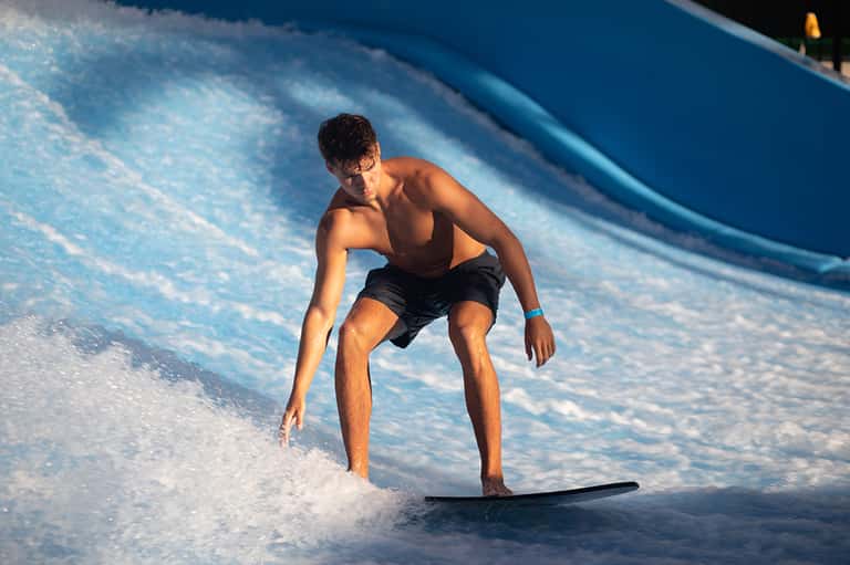 Young man surfing on a wave in bright blue ocean water during daytime
