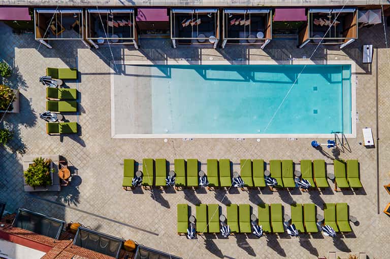 Overhead view of resort pool with lime green lounge chairs and windows of building above