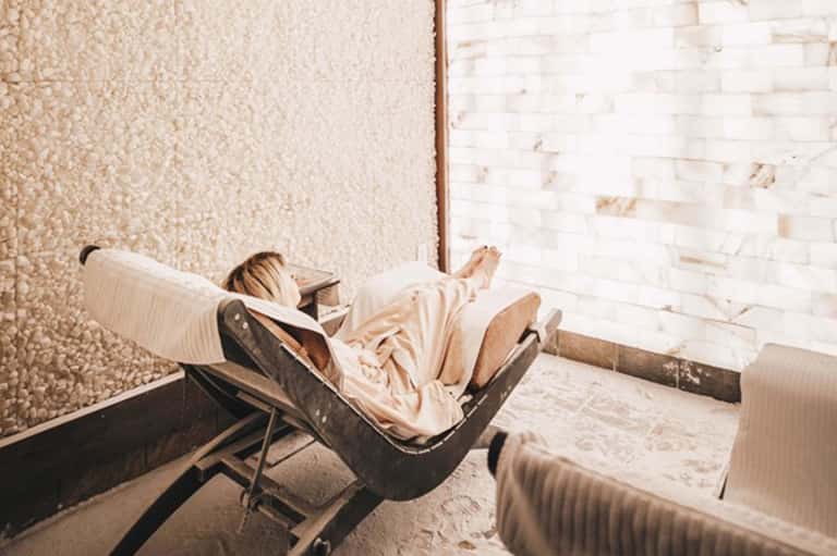 Person relaxing in lounge chair in minimalist brick-walled interior space