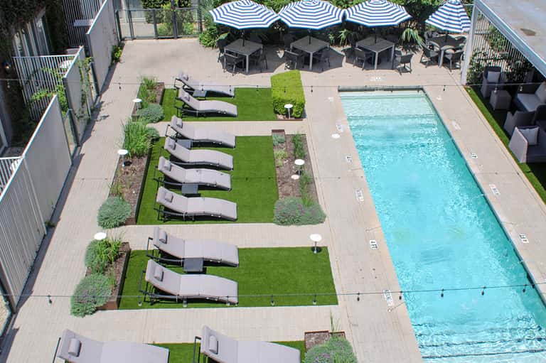 Aerial view of rectangular lap pool with lounge chairs and umbrellas on wooden deck