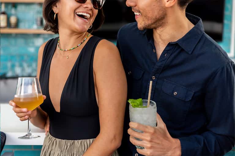 Two guests enjoying cocktails at a poolside bar with turquoise tile backdrop
