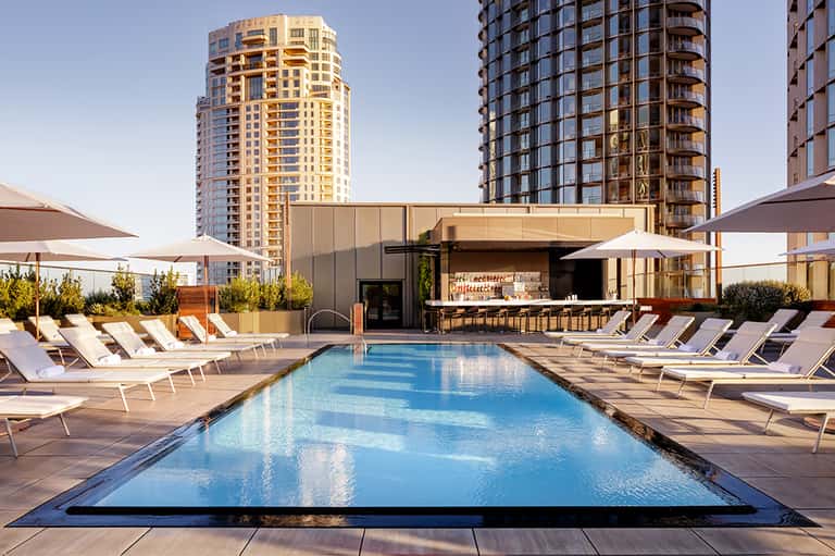 Rooftop pool with loungers and bar at modern high-rise hotel overlooking city skyline