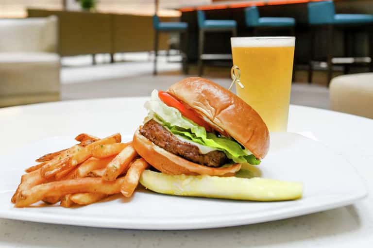 Gourmet burger with fries and beer on white plate at upscale restaurant patio