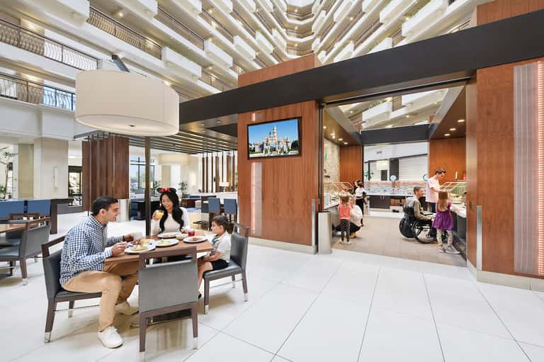 Contemporary hotel lobby and dining area with family enjoying meal, modern ceiling design, and open floor plan