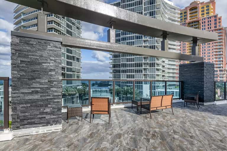 Modern rooftop terrace with stone columns, lounge seating, and downtown skyline views