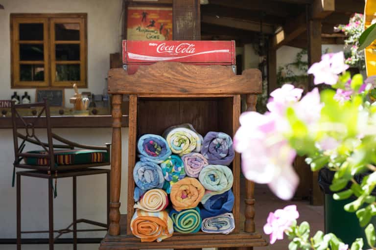 Wooden towel display with rolled colorful towels and Coca-Cola sign in courtyard setting