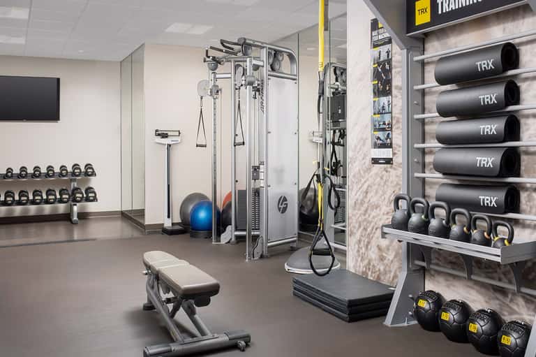 Modern fitness center with TRX training equipment, dumbbells, and cable machines