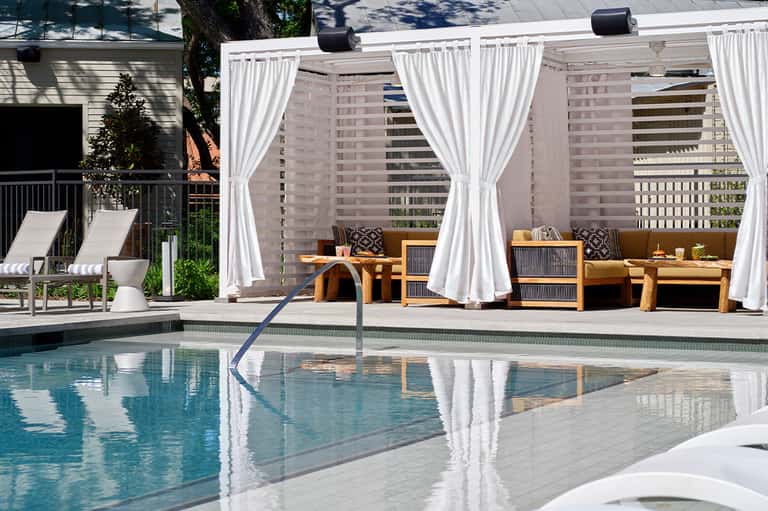 Luxury resort pool with white cabanas, lounge chairs, and high-rise buildings backdrop