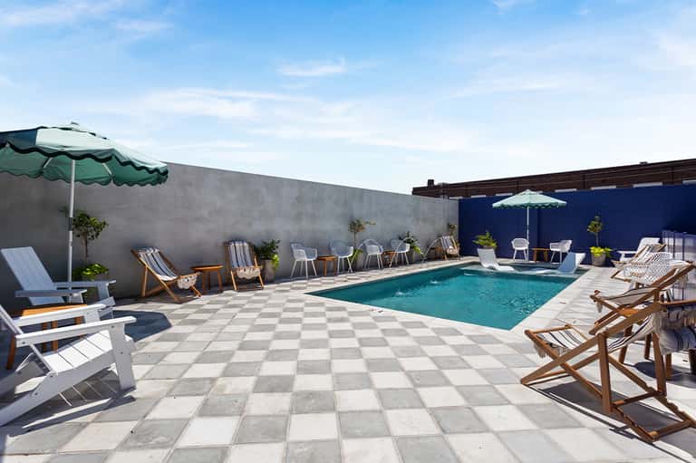 Modern rooftop pool deck with checkered pavers, lounge chairs, and umbrellas