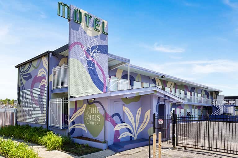 Modern motel building with colorful iris flower mural, two-story structure, and contemporary signage