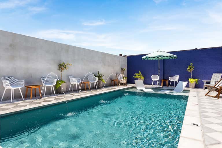 Contemporary rooftop pool with turquoise water, white loungers, and blue accent wall