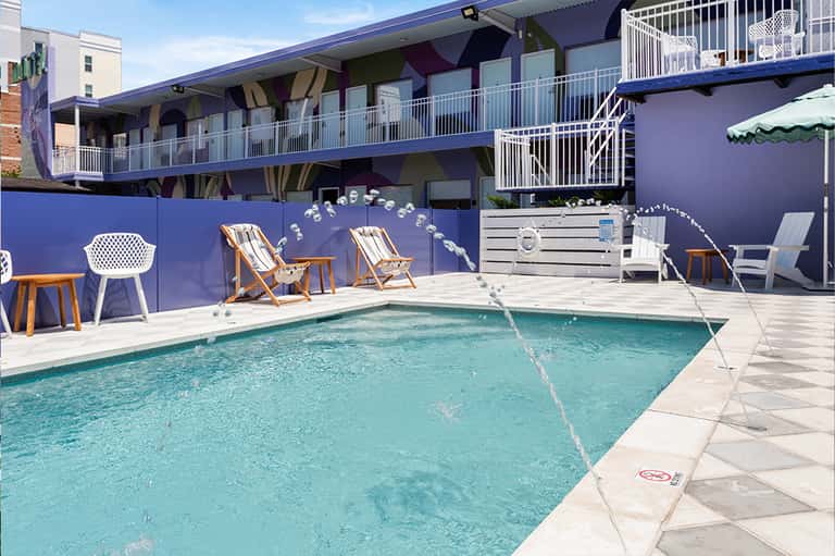 Contemporary pool area with bright blue accent wall, modern furnishings, and residential buildings