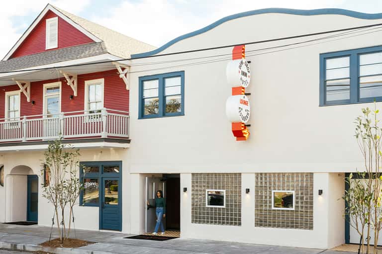 Modern mixed-use building with red cottage-style upper level and white contemporary lower level
