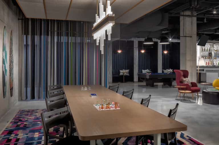 Modern conference room with long wooden table, colorful striped wall panels, and contemporary lighting