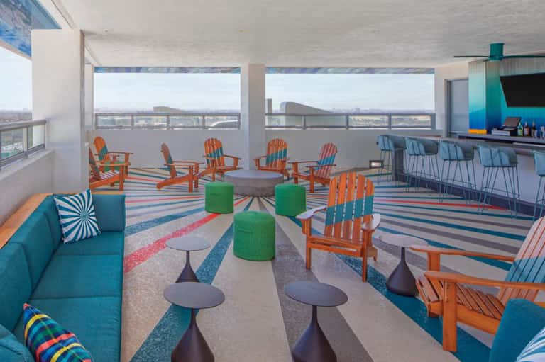 Rooftop terrace with colorful Adirondack chairs, striped flooring, and panoramic city skyline views