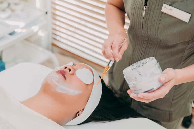 Spa professional applying facial mask treatment to client