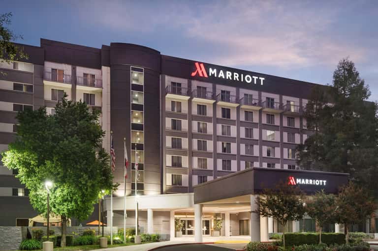 Marriott hotel exterior at dusk with illuminated façade, modern architecture, and manicured grounds with trees