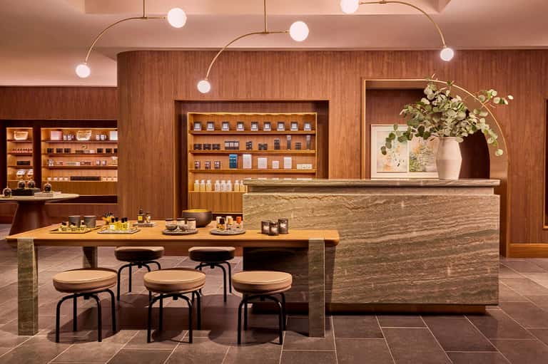 Luxury skincare boutique with wooden shelving, stone counter, organic product display, and modern pendant lighting