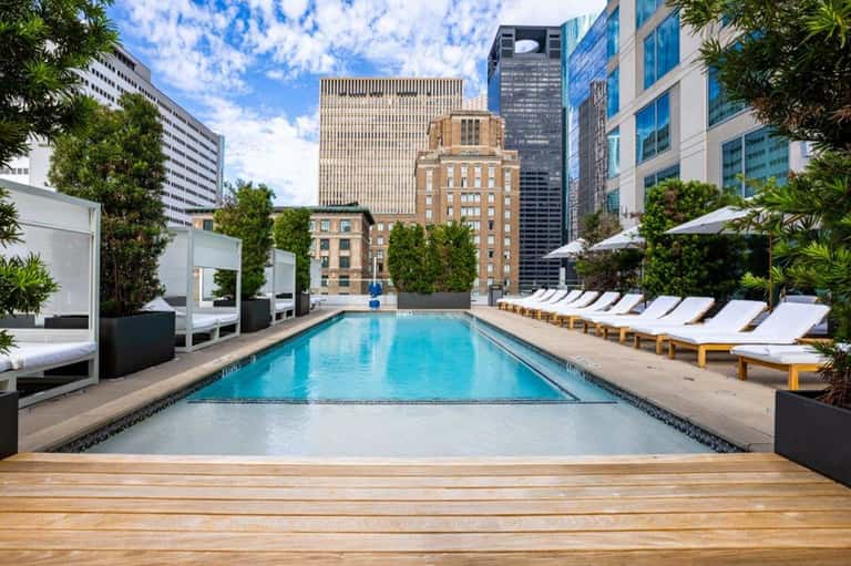 Rooftop pool with white lounge chairs overlooking downtown cityscape and historic buildings