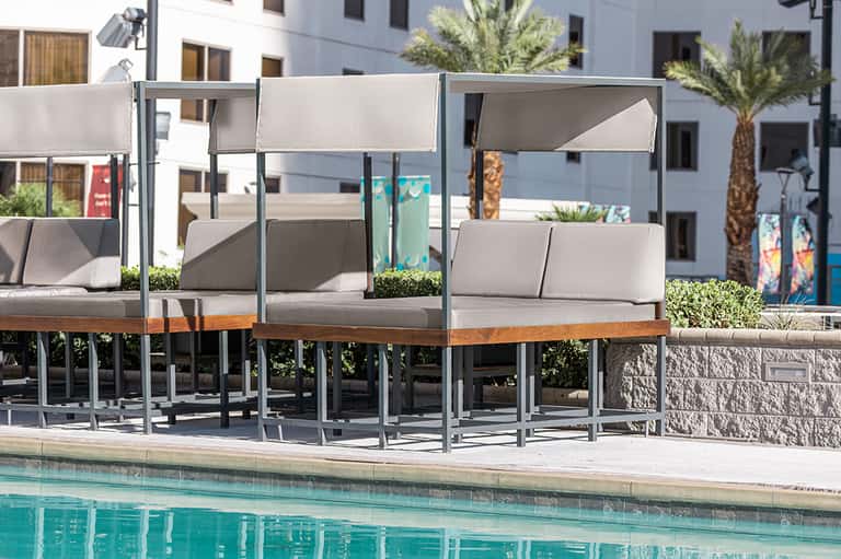 Pool lounge with modern gray cabanas and cushioned seating overlooking water