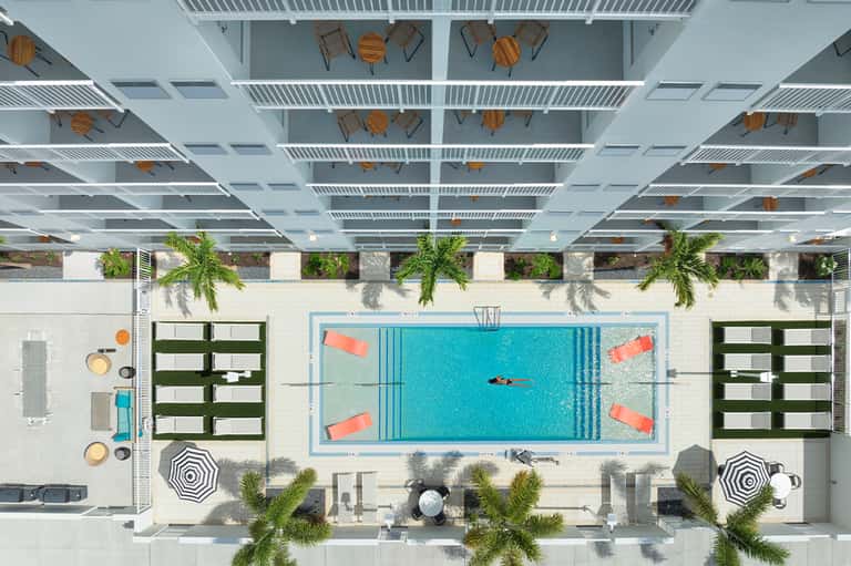 Overhead view of indoor pool with turquoise water, lounge chairs, and modern ceiling design